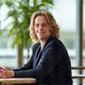 Anna Nieminen istuu toimistolla ja hymyilee