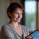 Nainen osallistumassa virtuaaliseen mindfulness-sessioon tablet-laitteen kautta, rauhallinen ilme.
